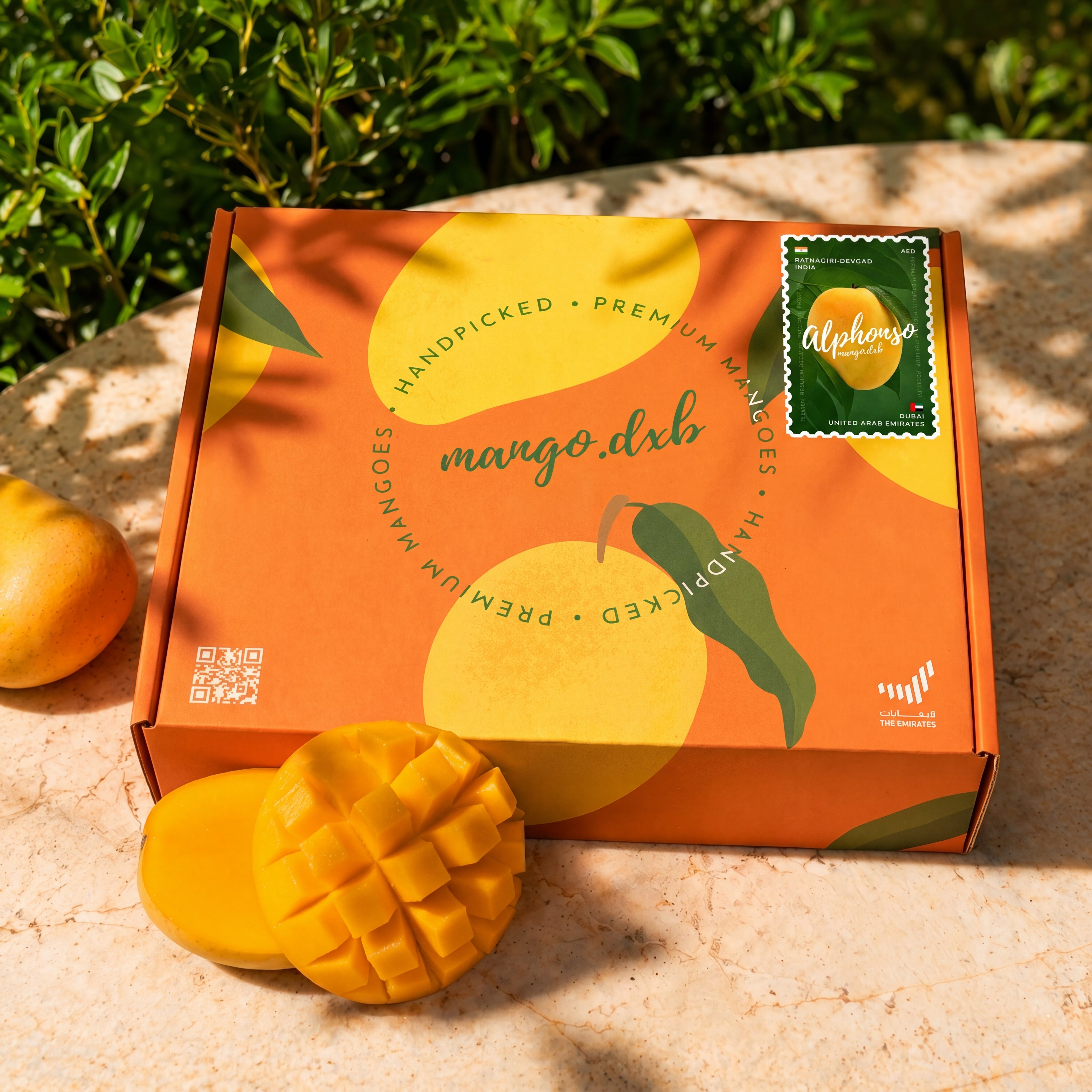 Mango.DXB box with a mango on a stone surface, surrounded by greenery